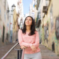 Relaxed young woman leaning on city stairs railing Por que cada vez mais brasileiros estão trocando Portugal pela Espanha?